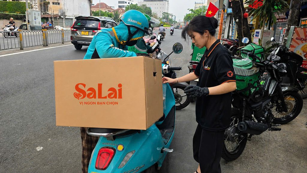 Nhân viên SaLai bàn giao thùng cơm hộp cho tài xế giao sự kiện